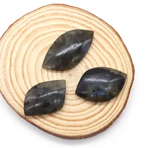 Three marquise-cut labradorite stones with blue fire on a natural wood block