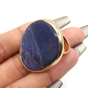 Detalle de anillo dorado ajustable con gran piedra ovalada azul oscuro en la mano