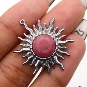 Dettaglio del ciondolo a sole bohémien con gemma rosa e finitura argentata lucida