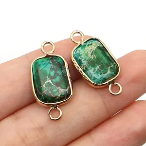 Macro shot of rectangular turquoise connector with gold trim held between fingers