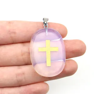 Détail macro d'un pendentif ovale en pierre violette avec un symbole de croix dorée