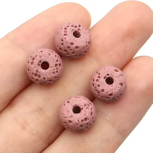 Macro detail of four pink porous volcanic lava diffuser beads held in palm for DIY jewelry