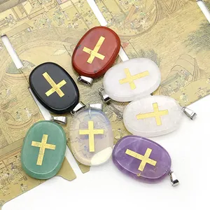 Lot de sept pendentifs ovales en pierre naturelle avec gravure de croix dorée et bélières