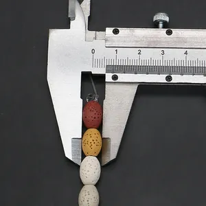 Detailweergave van ovale lava kralen die worden gemeten met een schuifmaat voor sieraden