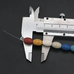 Detailweergave van gekleurde ovale lavasteen kralen gemeten met schuifmaat, maat 12 mm