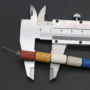 Macro shot of colorful cylindrical lava stone beads being measured with a caliper