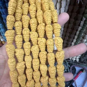 Macro shot of hand holding bright yellow cone-shaped porous lava stone beads for jewelry DIY
