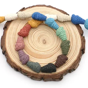 Bunte Lavastein-Perlen in Schneckenform für DIY-Schmuck auf rundem Holztablett