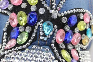 Nahaufnahme bunter Schmucksteine und Strasssteine auf dem Denim-Stoff der Schirmmütze