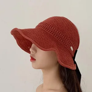 Close-up of terracotta knitted sun hat with mesh texture and elegant black ribbon bow