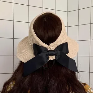 Detail of the oversized black bow on a beige woven open-top sun hat for women