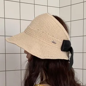 Detail of beige woven sun hat showing intricate crochet texture and black bow tie decoration