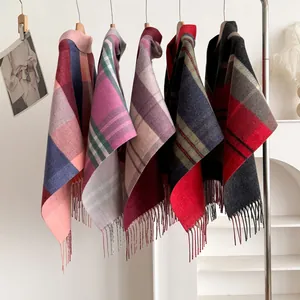 Detail view of multicolored plaid wool shawls with decorative fringe hanging on a rack