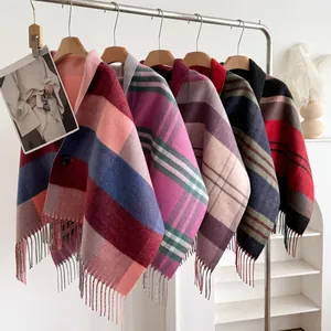 Multiple plaid wool ponchos with fringe trim and button detail in diverse colorways