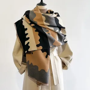 Close-up van sjaal met abstract golfpatroon, fijne franjes en warme winterse textuur
