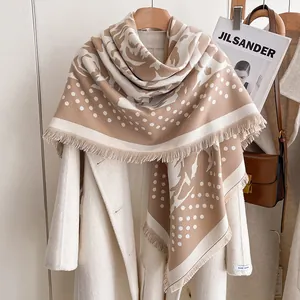 Beige and camel rose polka dot faux cashmere scarf with fringes over a white wool coat