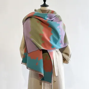 Kleurrijke dames sjaal van imitatie kasjmier met kwastjes gestyled op een winterjas