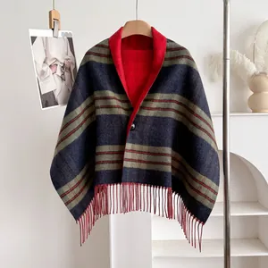 Detail of wool plaid shawl with long tassels and red lining hanging on wood hanger