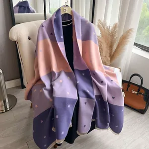 Women's heart pattern color-block cashmere-feel scarf with fringes on a white sofa