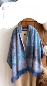 Blue cashmere scarf with forest patterns and fringe tassels hung on a hanger