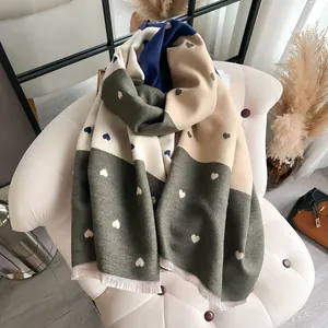 Close-up of dual-sided cashmere scarf with heart patterns and tassel fringe details