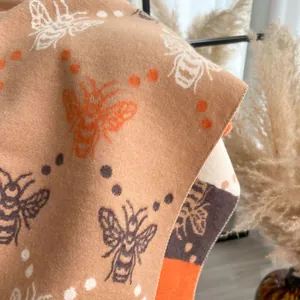 Detalle de bufanda de cachemira sintética con patrón de abejas y textura de punto fino