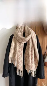Detail of geometric V-pattern knit texture and long tassels on beige winter scarf