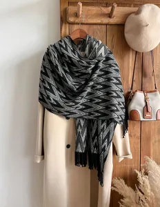 Detail view of black and white geometric wave knit scarf with long fringes and thick texture