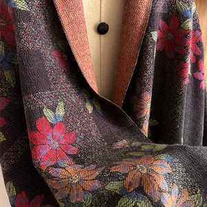Close-up of floral jacquard knit shawl with vibrant red flowers and thick wool texture