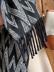Close-up of geometric jacquard pattern and black fringe on a soft winter knit scarf