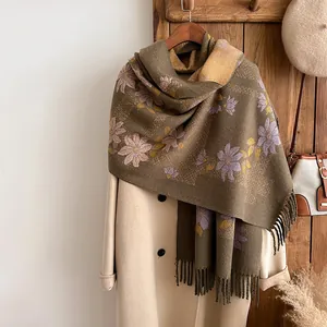 Olive green cashmere scarf with floral patterns and tassels on white coat