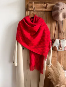 Close-up of red zigzag pattern scarf with long tassels and beige wool coat details