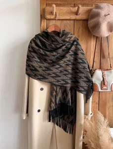 Detail of geometric pattern scarf with long tassels hanging on a wooden wall