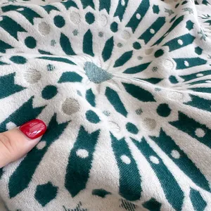 Macro view of thick knitted texture with dark green geometric pattern on a warm wool shawl