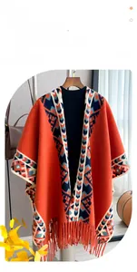 Detail of orange cashmere shawl with fringe and geometric tribal pattern on a hanger
