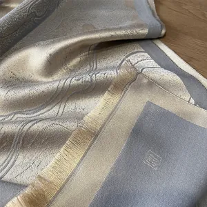 Macro view of gold jacquard patterns and gray fabric texture with fringe details
