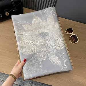Detail of grey cashmere-like scarf with golden lotus patterns on a gold display tray