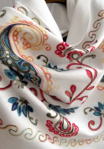 Nahaufnahme der floralen Paisleystickerei auf einem weichen weißen Winter-Pashmina