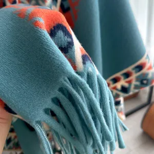 Detailed view of light blue bohemian poncho featuring geometric patterns and long fringes