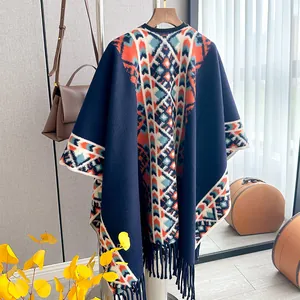 Detail of bohemian geometric knit poncho featuring long fringes and thick fabric texture