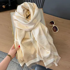Detail of elegant gold silk scarf featuring fine linear clouds and delicate tassel fringe
