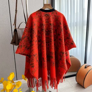 Détail du poncho en cachemire rouge vintage avec motifs noirs et longues franges