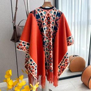 Close-up of orange bohemian poncho featuring geometric knit patterns and tassel details