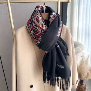Écharpe ethnique noire en cachemire brodé avec franges sur manteau beige