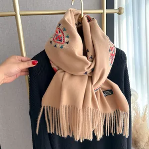 Détail de broderie florale ethnique sur un châle en laine de cachemire beige à franges