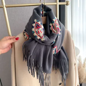 Détail de la broderie florale ethnique sur un châle gris foncé avec de longues franges