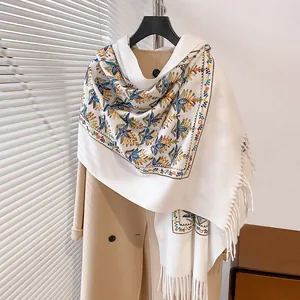 Sciarpa bianca in cashmere con ricami floreali e nappe su cappotto di lana