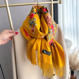 Detail of floral embroidery on mustard yellow cashmere wool scarf with soft tassel fringe
