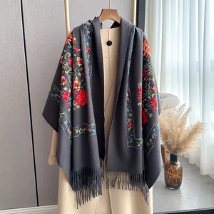 Detailed view of colorful floral embroidery and fringes on dark grey pashmina shawl