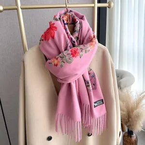 Pink wool cashmere scarf with vintage floral embroidery and fringe hanging on a coat